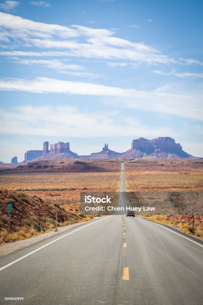 Road Leading to Oljato-Monument Valley A car driving on a road with a picturesque view of Monument Valley in the backdrop. Highway Stock Photo
