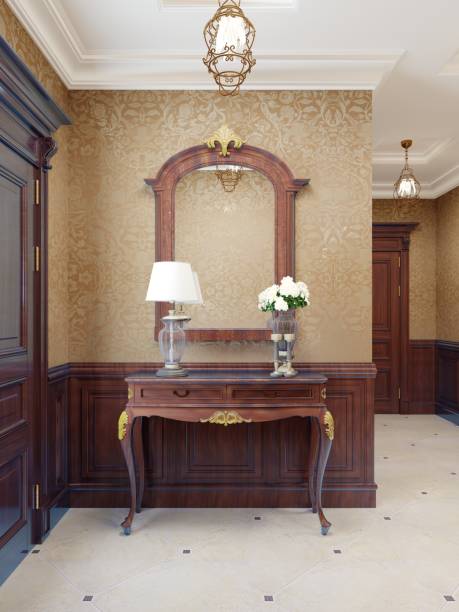 istock Console key table with mirror in wooden frame and table lamp. Classic hallway interior with patterned yellow wallpaper and brown wood paneling. 1249532364