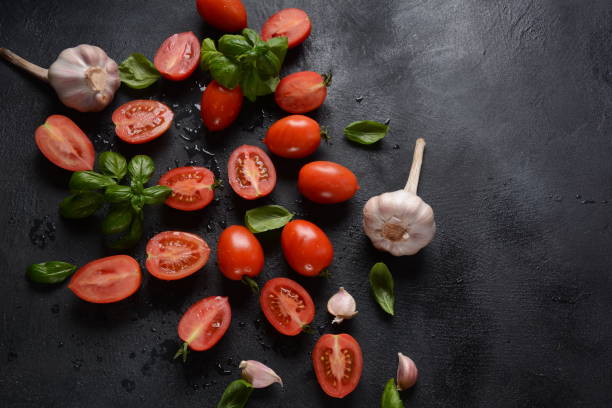 istock Pieces of cut fresh tomatoes over dark background. 1249545241