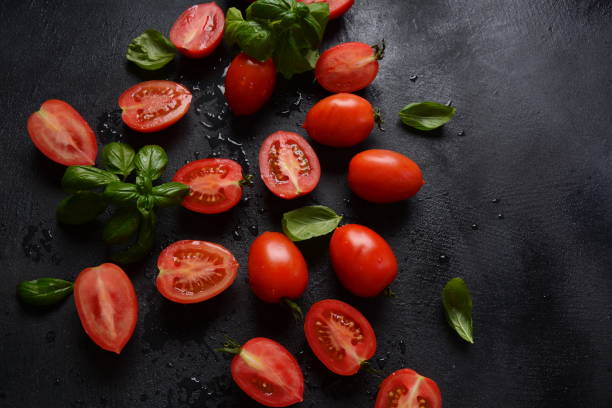 istock Pieces of cut fresh tomatoes over dark background. 1249545353