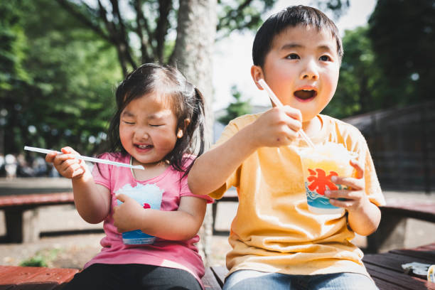 istock Siblings eating shaved ice in the park 1249546905