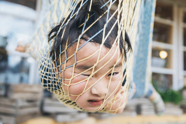 Boy playing on hammock Asian boy putting his head into net of hammock. child arrest stock pictures, royalty-free photos & images