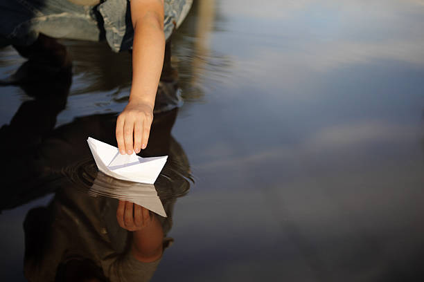 istock Child playing with a paper boat in a puddle 124954813