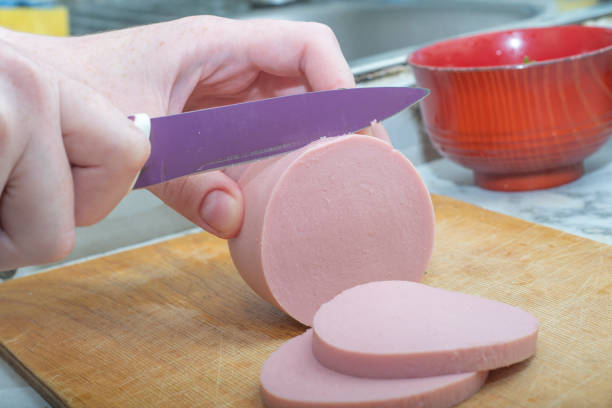 istock Close-up - hands cut soft pink sausage with a knife 1249548984