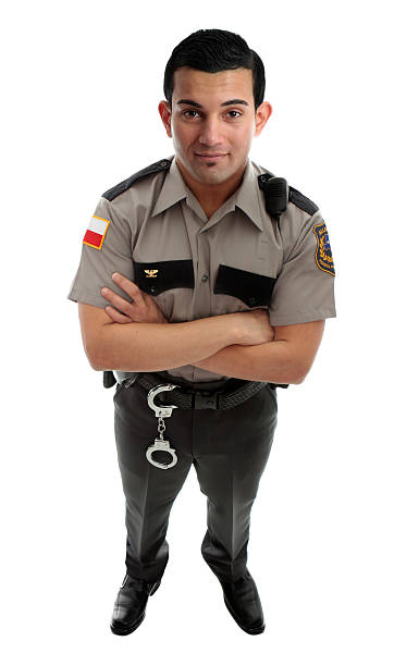 Prison Guard Warden or Policeman A male prison guard warden or policeman in uniform with duty belt and radio unit.   Standing with arms crossed and looking up.  White background prison guard stock pictures, royalty-free photos & images