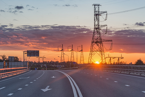 High-voltage towers and new highway at sunset time.