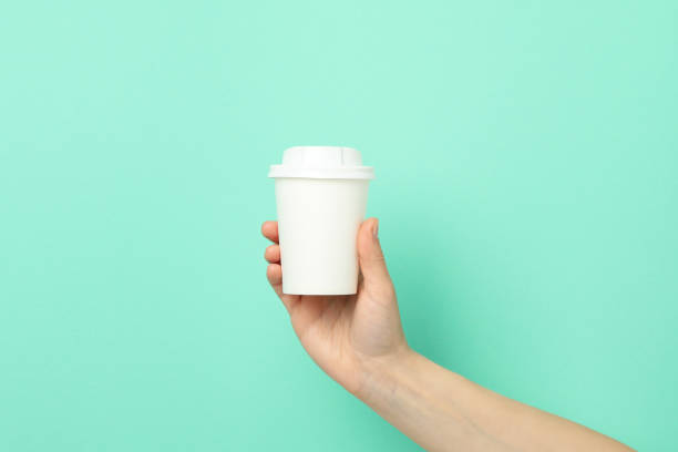 istock Female hand holds paper cup on mint background, space for text 1249552725