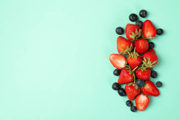 istock Tasty red strawberry and blueberry on mint background, top view 1249557909