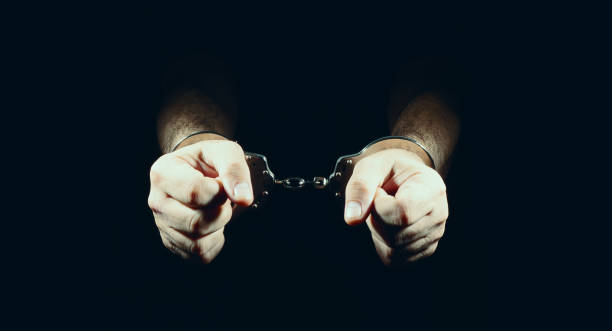 istock hands and handcuffs, in dark background. 1249558115