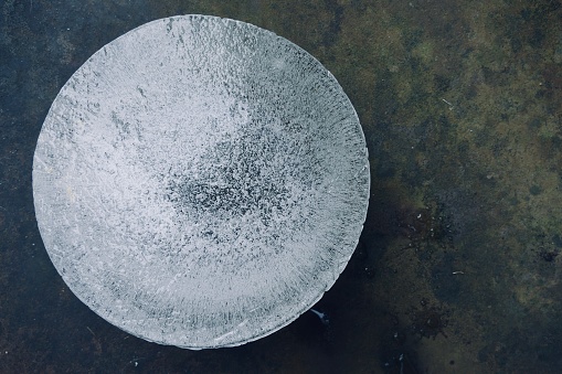 Round ice block surrounded by a dark green background