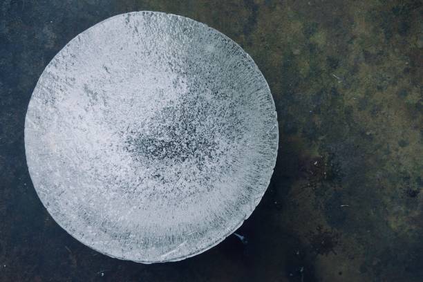 Round ice block surrounded by a dark green background stock photo
