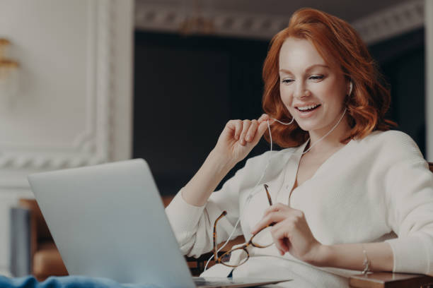istock Satisfied happy foxy successful woman has video conference, uses modern laptop computer and earphones, browses data and works on remote project, poses in modern apartment, watches online webinar 1249565526