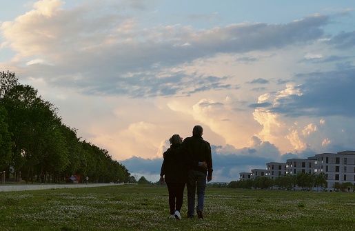 The silhouette of a couple in front of the thunderclouds on the evening horizon