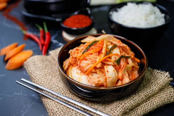 Photo of Eating kimchi cabbage and rice in a black bowl with chopsticks, Korean food.