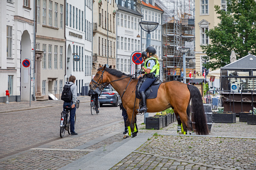 Gammel Torv, Copenhagen, Denmark, June 8, 2020: Two young female police constables on horseback in a city square.