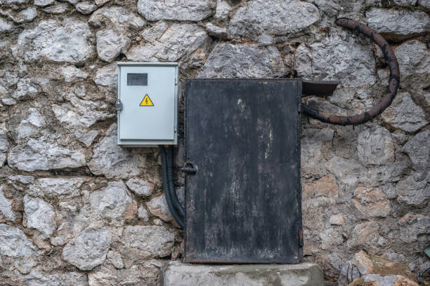 istock Old and new electrical boxes on a rough stone wall 1249567898