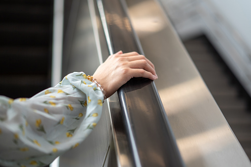 Close up of young woman right hand holding escalator handrail