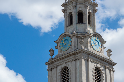 Isolated St Martin-In-the-Fields church clock tower against blue sky and clouds, closeup, London, UK
