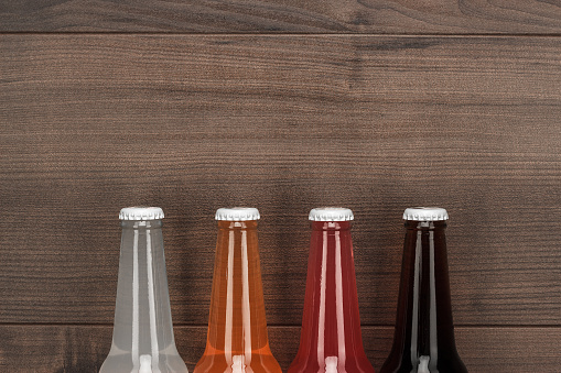 glass bottles of different sweet drinks on wooden table