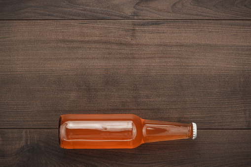 glass bottle of orange soda drink on wooden background