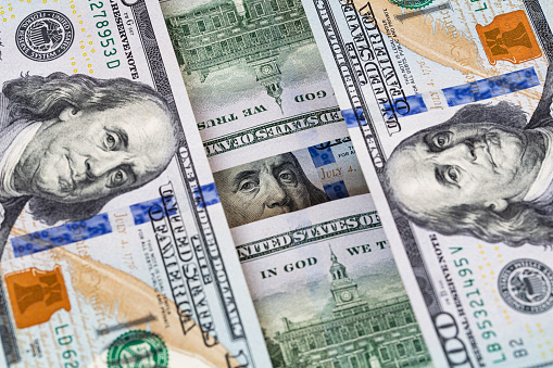 Benjamin Franklin peeking through 100 dollar banknotes