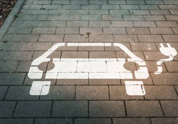 A white electric car sign on the ground