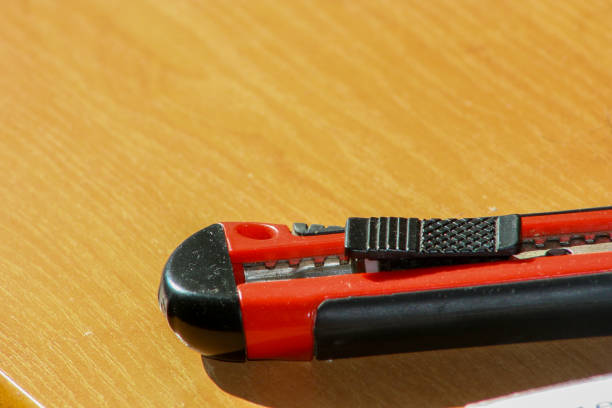 istock Red knife cutter on wooden table. 1249586263