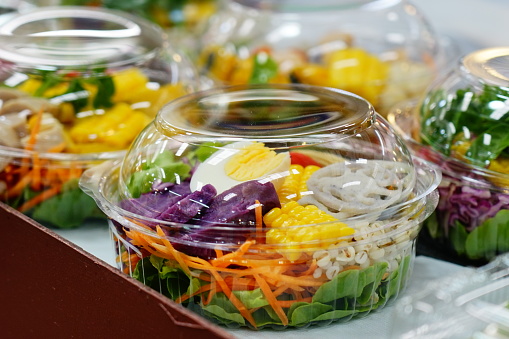 Salad of fresh vegetables and healthy fruit in clear plastic box  for sale in market