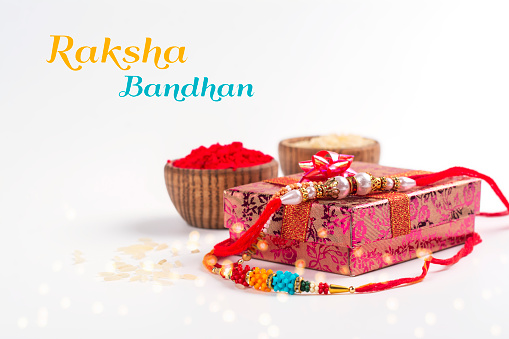 Indian festival Raksha Bandhan background. Indian rakhi bracelets, presents, rice and kumkum in bowls on white. Copy space