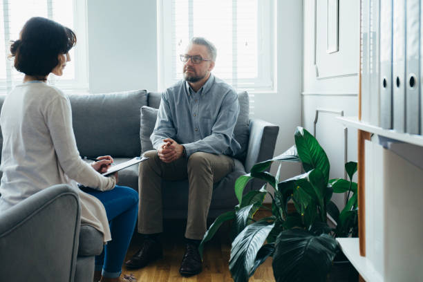 istock Handsome man sitting on a gray sofa during a meeting with a psychotherapist 1249588973