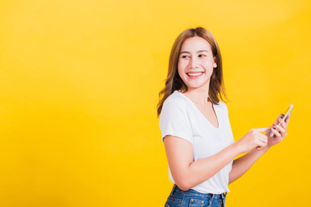 istock Woman standing smile, holding mobile phone looking back to space 1249589118