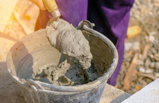 istock hand with old trowel and bucket with mortar at consturction site 1249590673