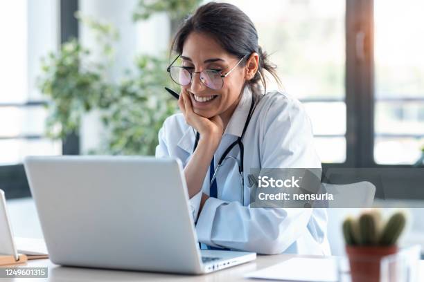 Lächelnde Ärztin Arbeitet Mit Ihrem Laptop In Der Beratung Stockfoto und mehr Bilder von Arzt