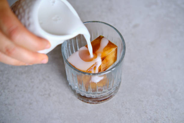 istock Coffee ice cubes in glass, pouring coconut milk. preparing refreshing coffee drink. 1249601495