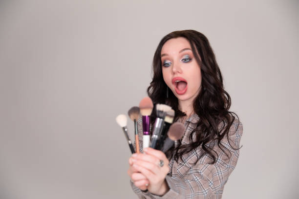 istock Girl makeup with brush cosmetics on a white gray background 1249601651