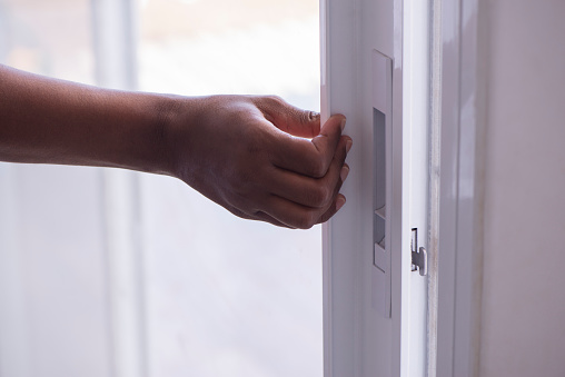 Image of female's right-hand opening / closing a patio door, touching, holding, pushing a sliding patio door handle.