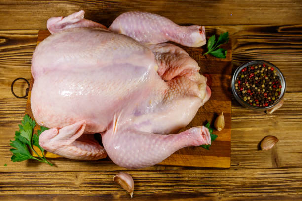 istock Raw whole chicken with spices on a wooden table. Top view 1249609603