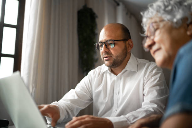 Advisor helping a senior woman at home (or mother and son) Advisor helping a senior woman at home (or mother and son) financial item stock pictures, royalty-free photos & images