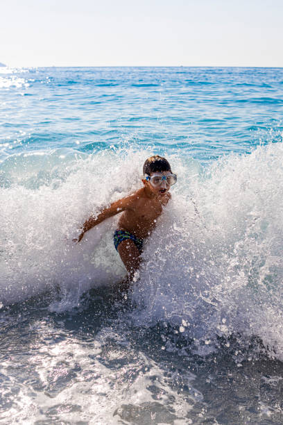 istock Little kid enjoying the waves on Myrtos beach, Greece. 1249610851