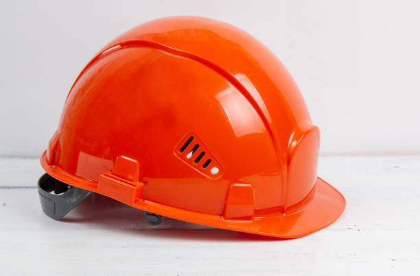 istock orange safety helmet on white wooden table 1249611085