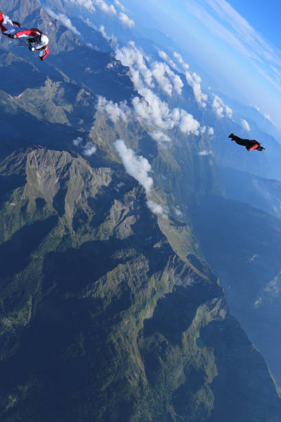 istock Wing suit fliers glide through blue skies 1249614153