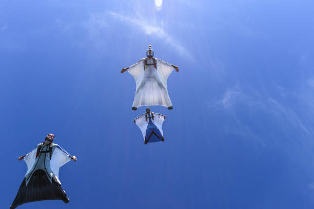 flügelanzug-flieger gleiten im einverspielen durch blauen himmel - clothing anticipation central europe switzerland stock-fotos und bilder