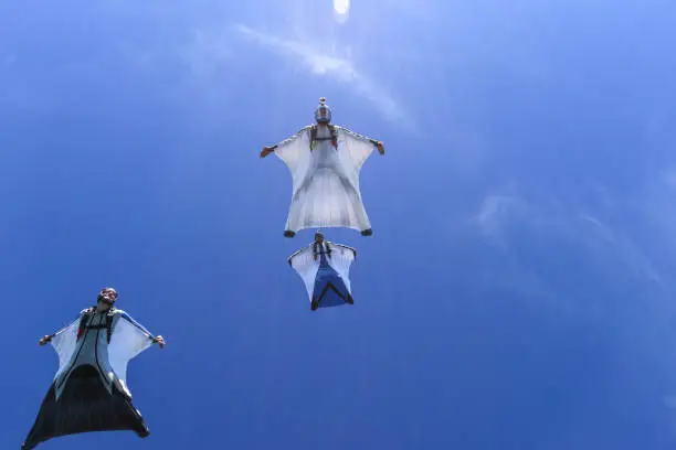 Photo of Wing suit fliers glide through blue skies in unison