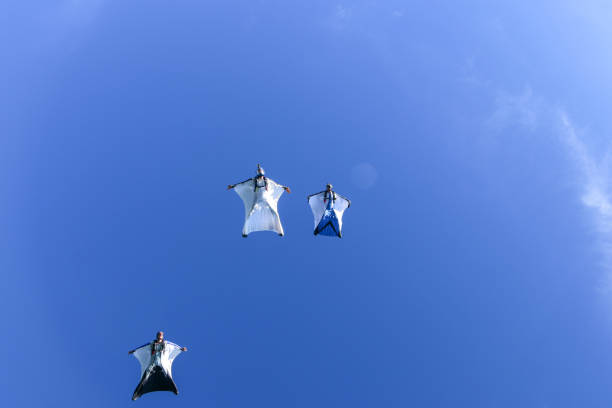 istock Wing suit fliers glide through blue skies in unison 1249615572