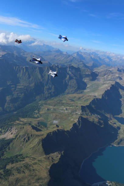 istock Wing suit fliers glide through blue skies in unison 1249615586