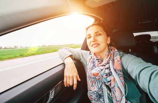 istock Woman making a selfie photo using smartphone and enjoying the fast car moving speed while she have a trip on the co-driver seat on the highway road. Safety car driving and people traveling concept. 1249616689