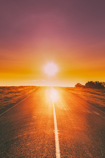 Sun Rising Above Asphalt Country Open Road In Sunny Sunrise Morning. Open Road In Summer Or Autumn Season At Sunny Sunset Evening.