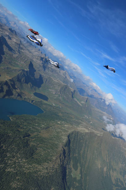 istock Wing suit fliers glide through blue skies in unison 1249618787