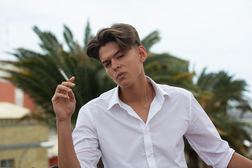 Portrait of young man smoking cigarette on rooftop.