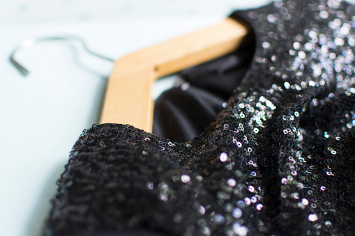 Black women dress. Dress in sequins, expensive. Close view. Clothes on a hanger.